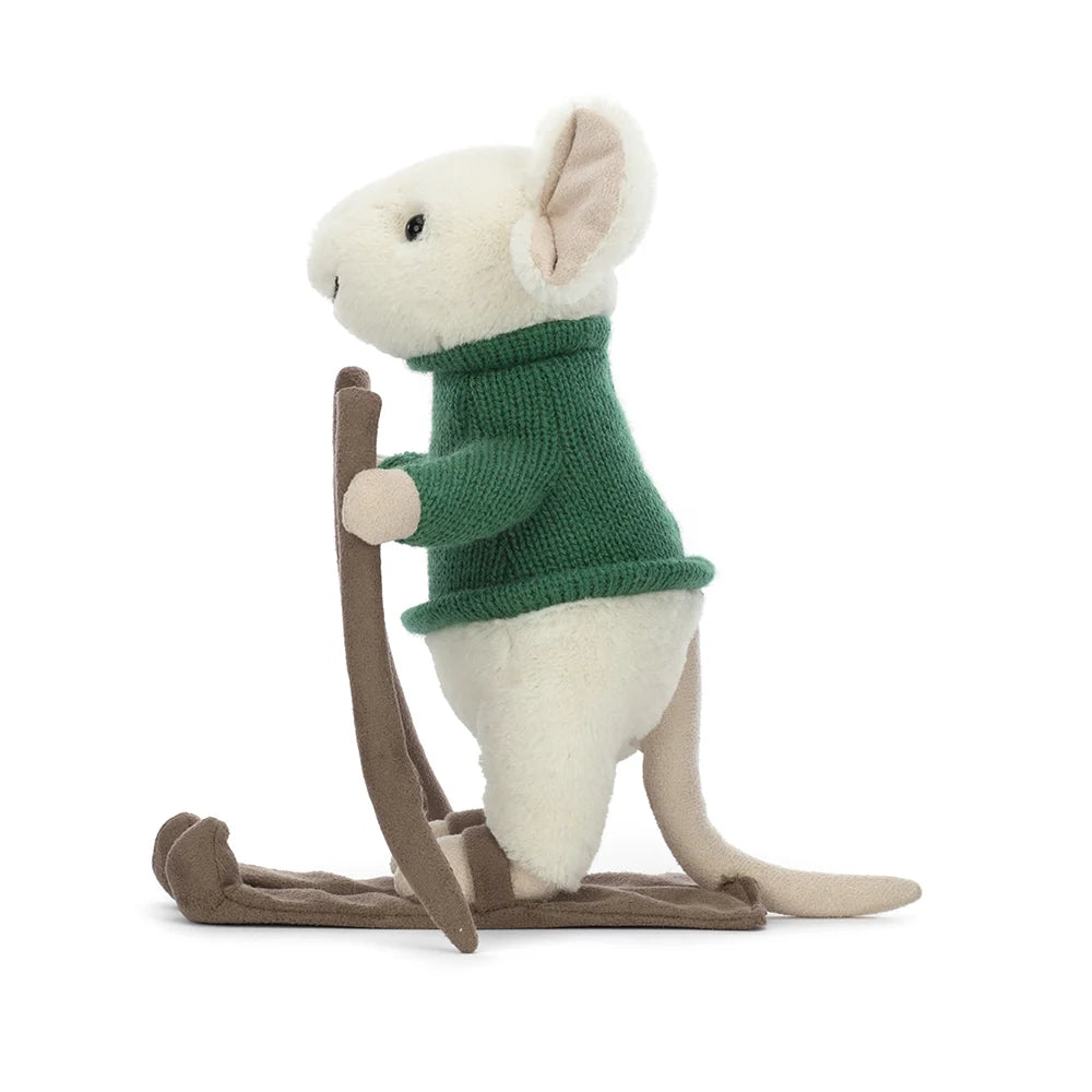 Profile view of toy: An adorable plush toy of a white mouse dressed in a cozy green sweater and skis strapped to its tiny feet. Its white fur contrasts beautifully with the vibrant green sweater. The merry mouse has a cheerful expression, with its sparkling black eyes and a sweet little nose peeking out from its furry face. As it glides down the slopes, the mouse's long tail playfully trails behind.